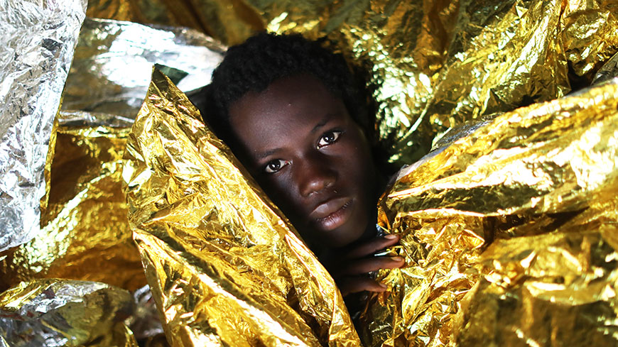 Guinean migrant child covered with thermal blankets following a rescue operation at sea by a Spanish NGO ©Giorgos Moutafis