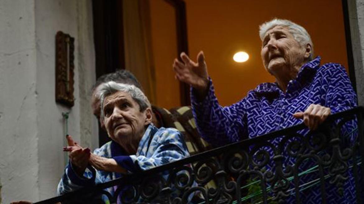 Elderly women stand on a balcony in Pamplona, Spain, on 15 March 2020.